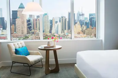 a bedroom with a table and a chair and a window at Ink 48 Hotel in New York