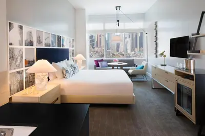 a bedroom with a large white bed and a living room at Ink 48 Hotel in New York
