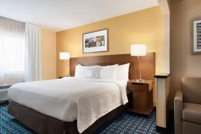 a hotel room with a large bed and a chair at Fairfield Inn by Marriott Deptford in Deptford