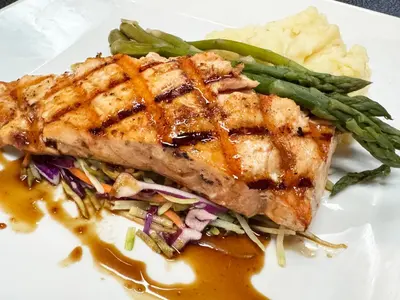 a white plate with a piece of pork chop and vegetables at City Hall Grand Hotel in Williamsport