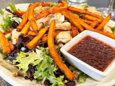 a plate of food with a salad and french fries at City Hall Grand Hotel in Williamsport