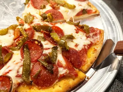 two slices of pizza with pepperoni and green peppers on a plate at City Hall Grand Hotel in Williamsport