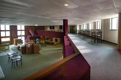 a large room with a staircase and a living room with tables and chairs at Carriage House Country Club in Pocono Manor
