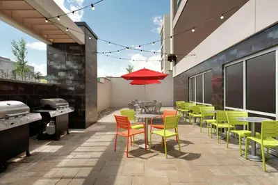 a patio with colorful chairs and tables and a grill at Home2 Suites by Hilton Middletown in Middletown