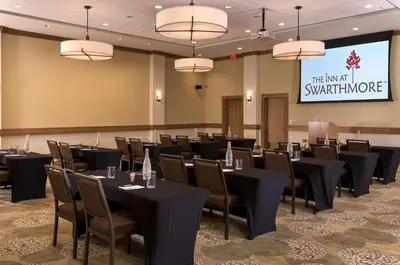 a conference room with tables and chairs and a screen at The Inn At Swarthmore in Swarthmore