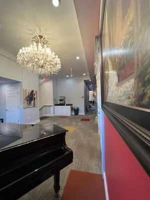 a hallway with a piano and a chandelier at Chateau Suites in Norristown