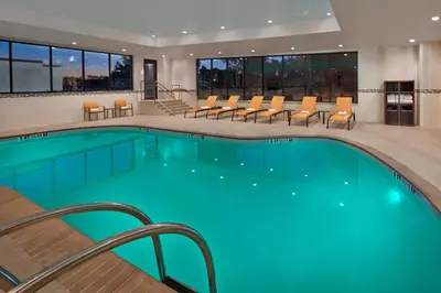 a pool in a hotel with chairs and a table at Courtyard by Marriott Philadelphia City Avenue in Philadelphia