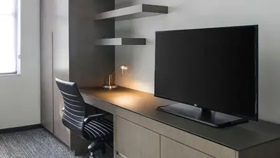 a room with a desk with a tv and a chair at Hyatt House Jersey City in Jersey City