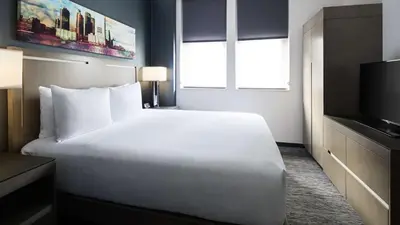 a hotel room with a white bed and a television at Hyatt House Jersey City in Jersey City