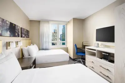 a hotel room with a bed and a desk with a tv at Doubletree By Hilton New York Times Square West in New York