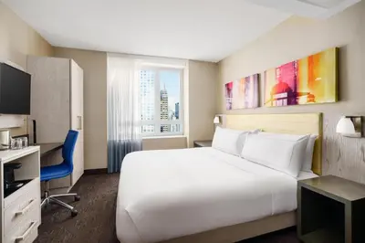 a hotel room with a large white bed and a desk at Doubletree By Hilton New York Times Square West in New York