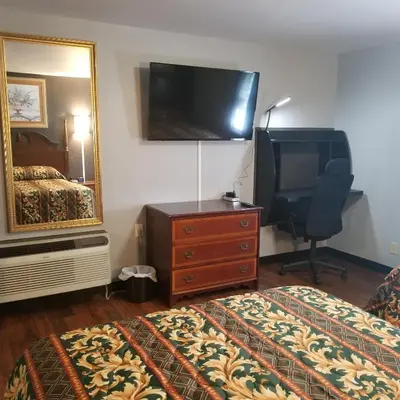 a hotel room with a bed and a dresser and a television at Cottage Inn - Grantville in Grantville