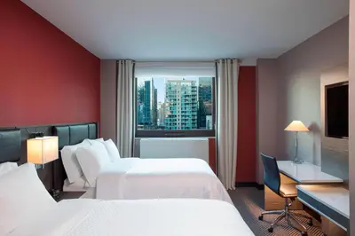 a hotel room with two beds and a desk and a window at Four Points by Sheraton Manhattan Midtown West in New York