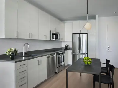 a kitchen with white cabinets and a table with a bowl of fruit at AKA University City in Philadelphia