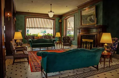 a living room with a green couch and a fireplace at Penn Wells Hotel in Wellsboro