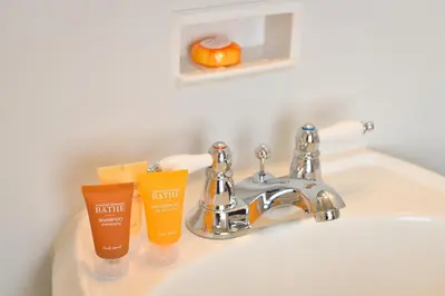 a sink with two bottles of sunscreen and an orange at Penn Wells Hotel in Wellsboro