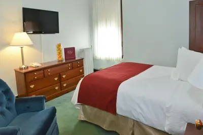 a hotel room with a bed and a chair and a television at Penn Wells Hotel in Wellsboro