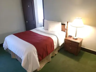 a bedroom with a bed and a lamp on a night stand at Penn Wells Hotel in Wellsboro