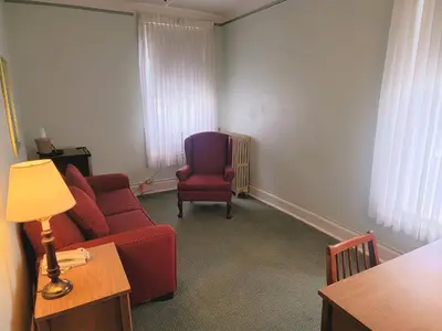a living room with a red couch and a chair at Penn Wells Hotel in Wellsboro