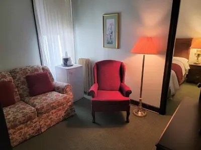 a room with a chair and a couch and a lamp at Penn Wells Hotel in Wellsboro