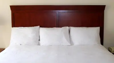 a bed with white sheets and a wooden headboard at Penn Wells Lodge in Wellsboro