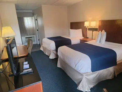 a hotel room with two beds and a desk with a television at Penn Wells Lodge in Wellsboro