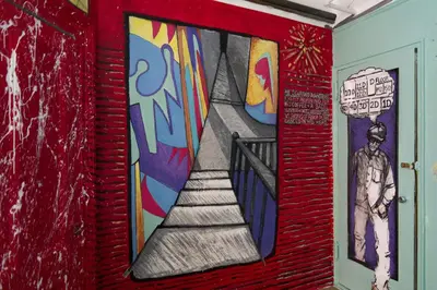 a mural on the wall of a hallway with a staircase at Carlton Arms Hotel in New York
