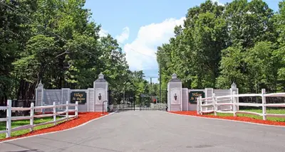a white gate with a white fence and trees at The Village at Pocono in Blakeslee