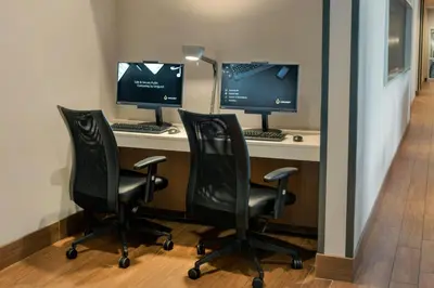 two computer monitors on a desk with two chairs at SpringHill Suites by Marriott Mount Laurel in Mount Laurel