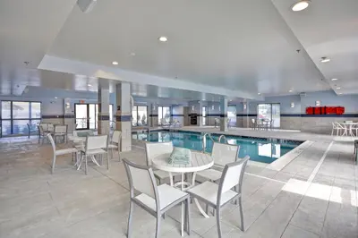 a swimming pool with a table and chairs next to a pool at TownePlace Suites by Marriott Cranbury South Brunswick in Cranbury