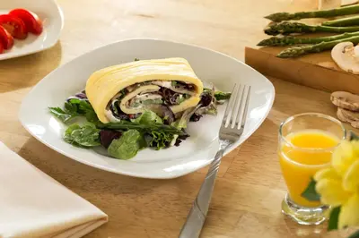 a plate with a sandwich and a salad and a glass of orange juice at Pheasant Field Bed and Breakfast in Carlisle
