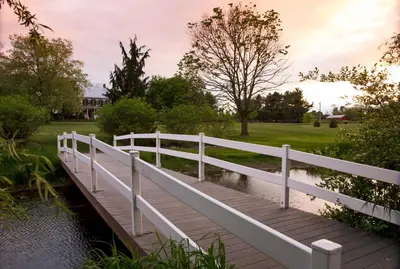 a white bridge over a river with a field at Pheasant Field Bed and Breakfast in Carlisle
