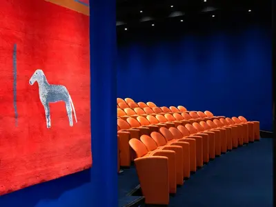 an auditorium with orange chairs and a painting of a horse at The Whitby Hotel in New York