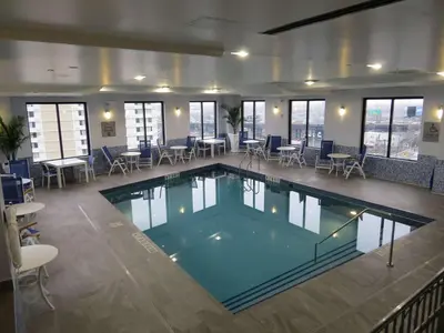 a large swimming pool in a building with tables and chairs at Best Western Premier NYC Gateway Hotel in North Bergen