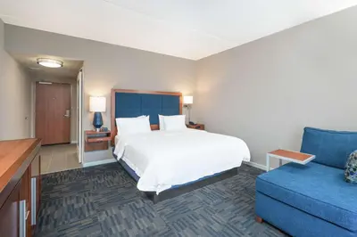 a hotel room with a bed and a blue couch at Hampton Inn & Suites Newburgh Stewart Airport, NY in Newburgh