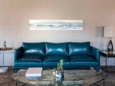 a blue leather couch in a living room with a table at Wm. Mulherin's Sons Hotel in Philadelphia