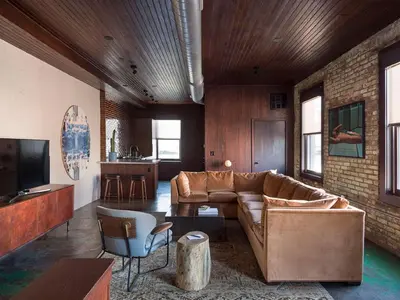 a living room with a brown couch and a kitchen at Wm. Mulherin's Sons Hotel in Philadelphia