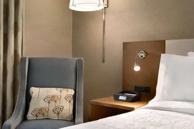 a bedroom with a bed and a chair with a pillow at Hilton Garden Inn New York Times Square South in New York