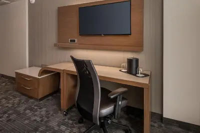 a desk with a chair and a television on a wall at Courtyard by Marriott Hershey Chocolate Avenue in Hershey
