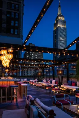 a rooftop patio with tables and chairs and a building at Moxy NYC Times Square in New York