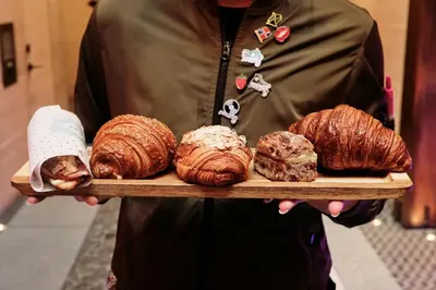 a person holding a tray of croissants and pastries at Moxy NYC Times Square in New York