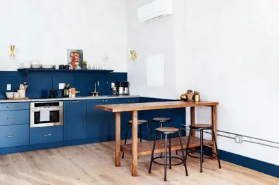 a blue kitchen with a wooden table and stools at Lokal Hotel Old City in Philadelphia