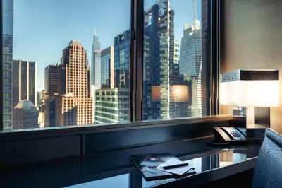 a room with a desk with a view of a city at W New York - Times Square in New York