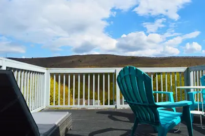a patio with two chairs and a table on a deck at Mountain View Suites in Jim Thorpe