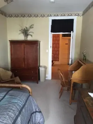 a bedroom with a bed and a dresser and a table at Victorian Charm Inn in Towanda