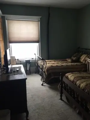 a bedroom with two beds and a desk and a window at Victorian Charm Inn in Towanda
