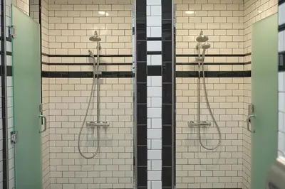 a shower in a bathroom with white tiles at West Village Eurohostel in New York