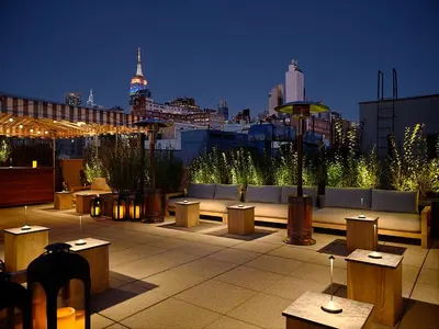 a rooftop patio with tables and benches and a city skyline at The Moore, New York City, a Member of Design Hotels in New York