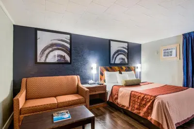 a hotel room with a bed and a chair at Highland Inn New Cumberland in New Cumberland