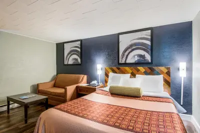 a hotel room with a bed and a chair at Highland Inn New Cumberland in New Cumberland